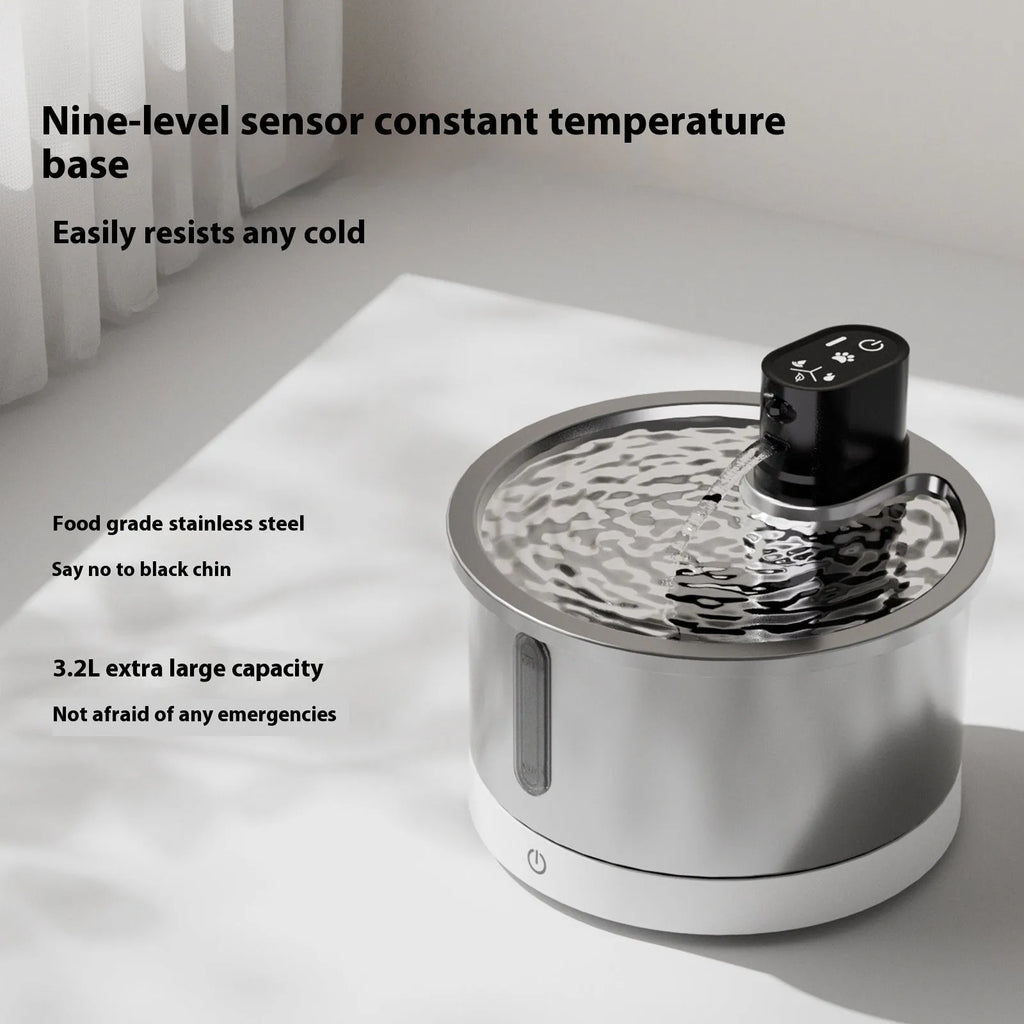 Stainless steel pet water fountain with a white heating base on a kitchen counter.