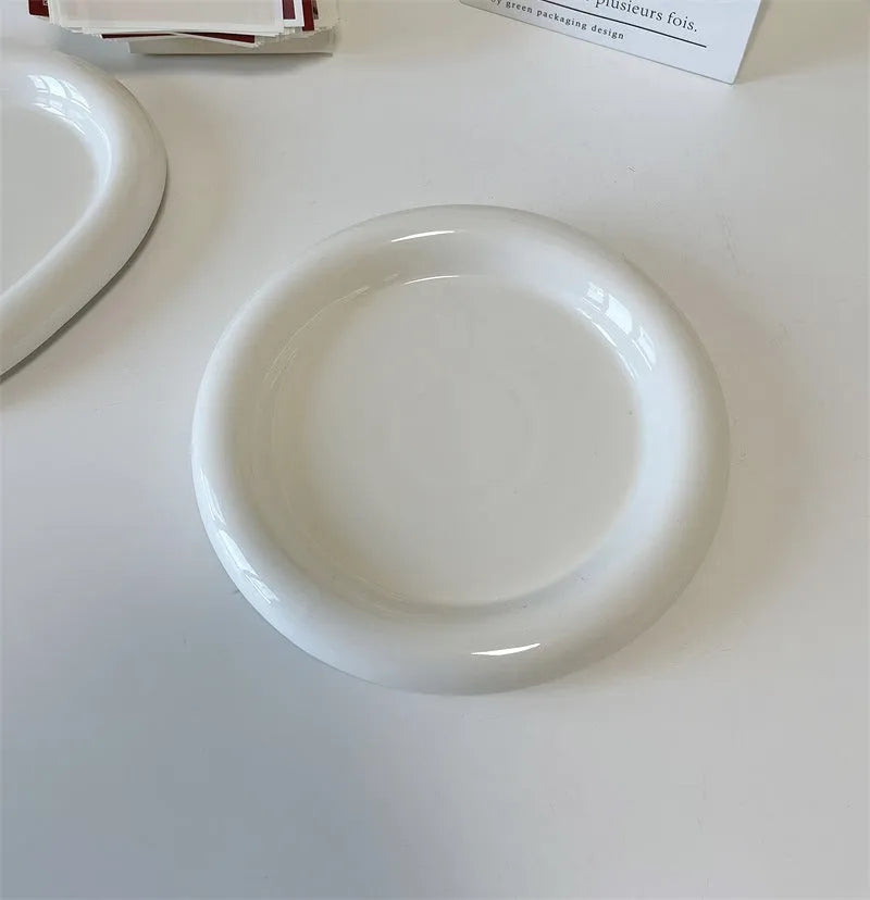 White ceramic plate with cartoon bear doodle design, shown next to round toot design plate, both microwave safe.