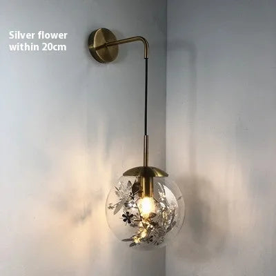 Modern golden flower glass wall lamp mounted beside a bed.