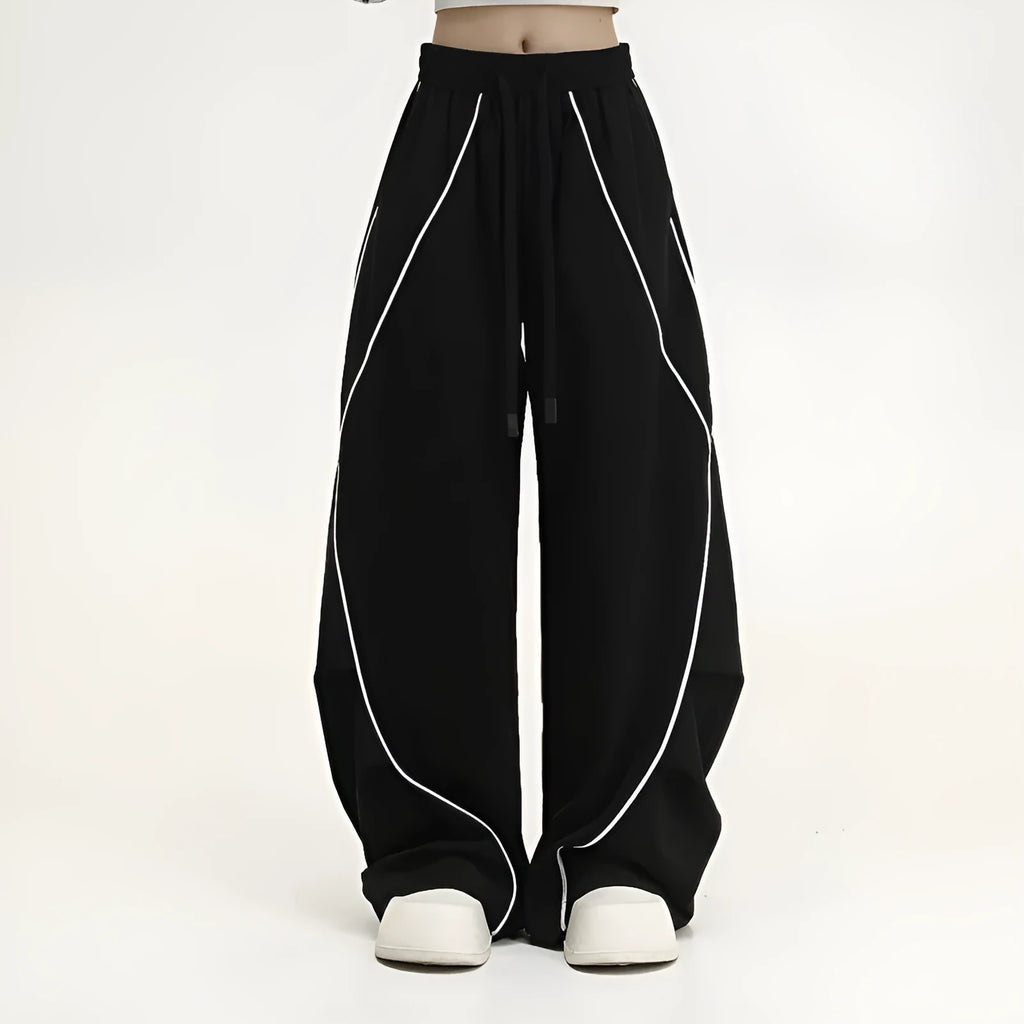 Black sports trousers with white stripes, showing wide-leg loose fit and mid-waist design.