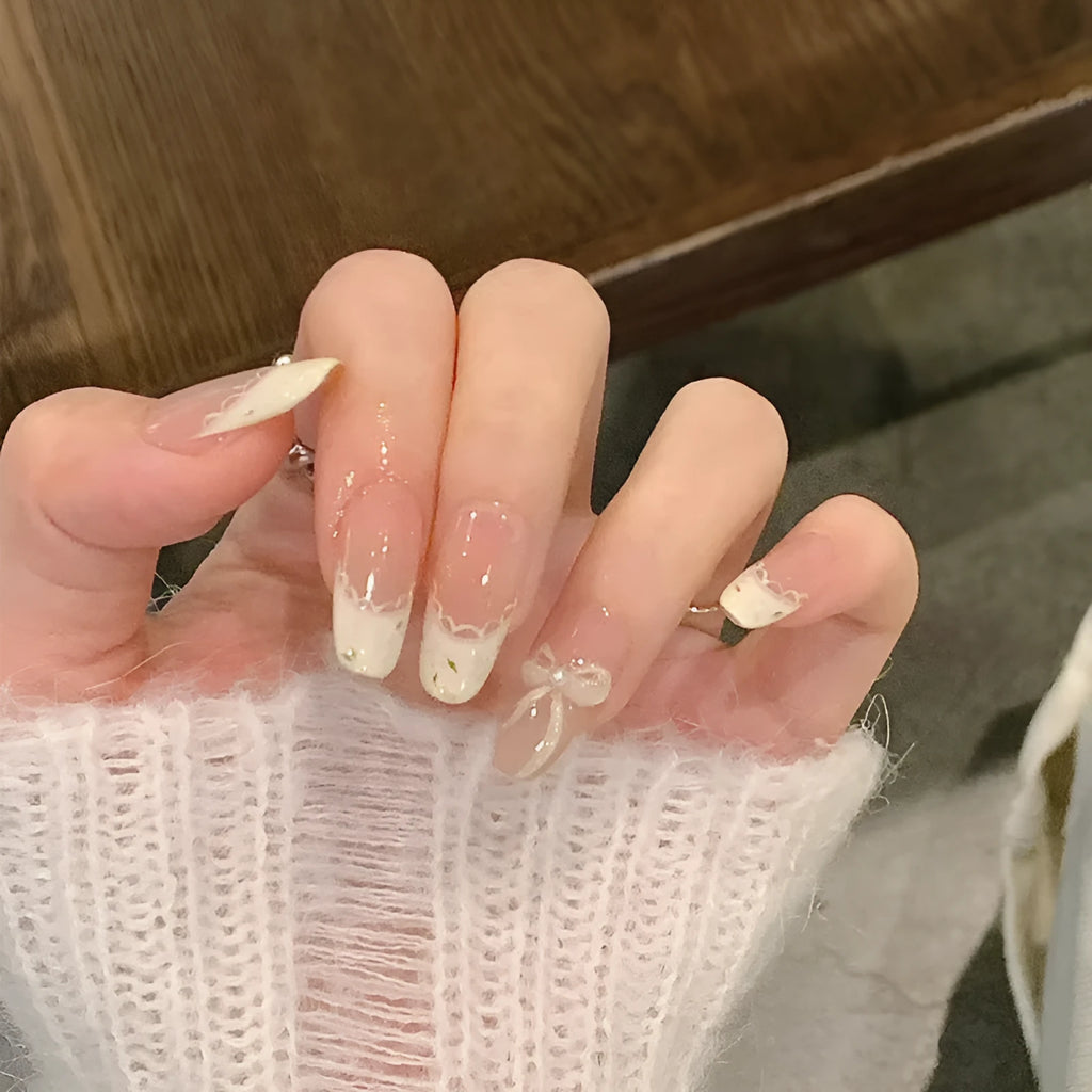 Set of medium-length coffin-shaped false nails with French manicure glitter tips and rhinestone decorations.