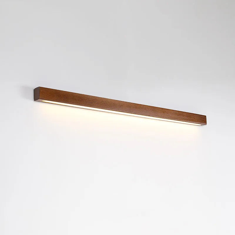 Walnut colour long wooden strip wall lamp with integrated LED lighting mounted on a wall.