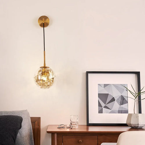 Modern golden flower glass wall lamp mounted beside a bed.