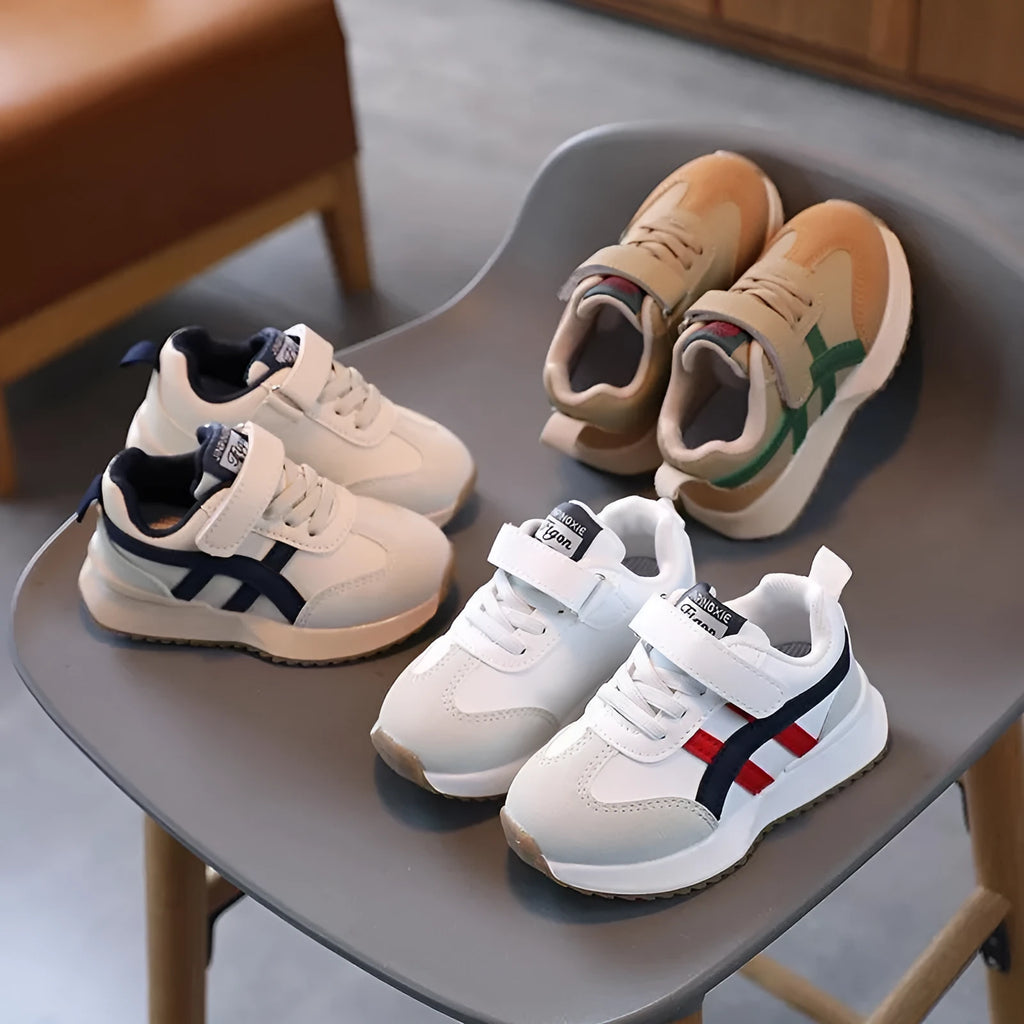 Children's solid-colour sneakers with Velcro strap closure and rubber sole.
