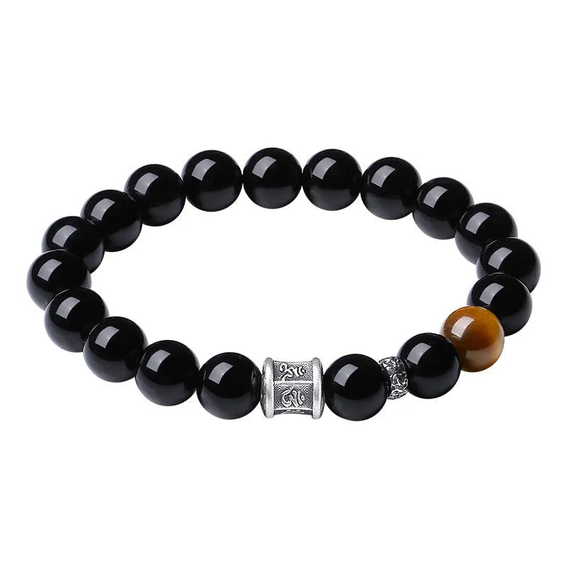 Black obsidian prayer wheel bracelet for men with a hand-woven silver clasp on a wrist.