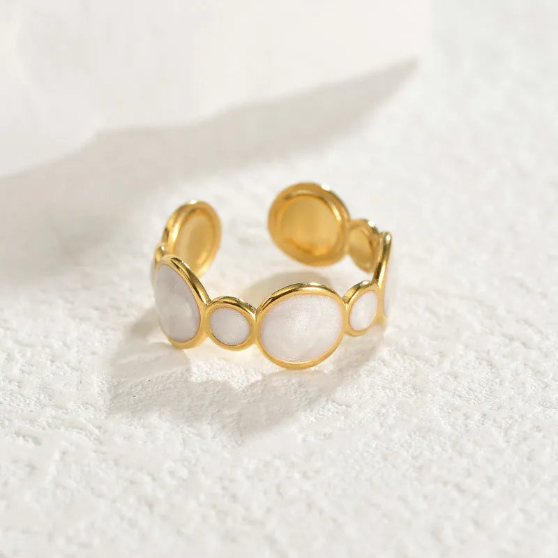 A stainless steel ring with a geometric design and adjustable opening on a plain background
