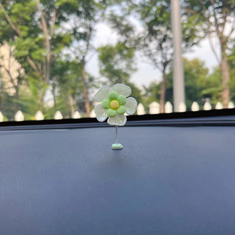 Small colourful plastic swing car decoration on a car dashboard, showing blue, green, pink, purple, and yellow colour options.