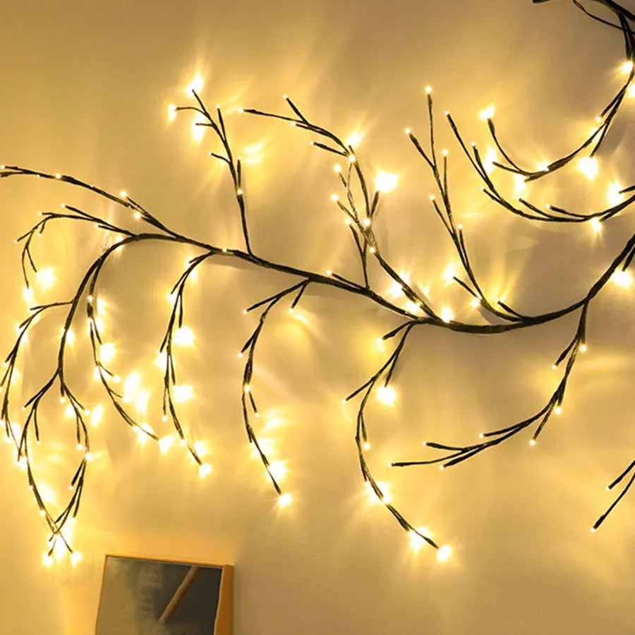 Flexible plastic LED willow vine garland with warm white lights bent into a decorative shape on a wall.
