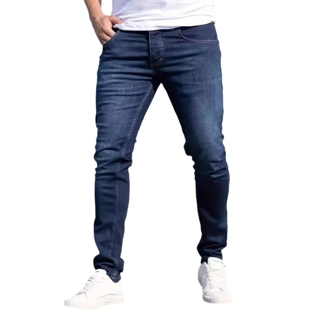 Dark blue men's slim-fit cotton jeans with a skinny leg opening on a plain background.
