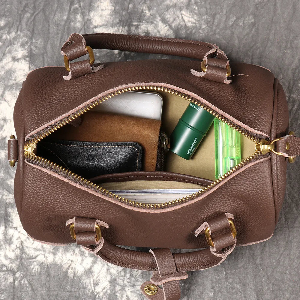 Brown yellow cowhide leather Boston bag with single shoulder strap, showing cylindrical shape and open outer pocket.