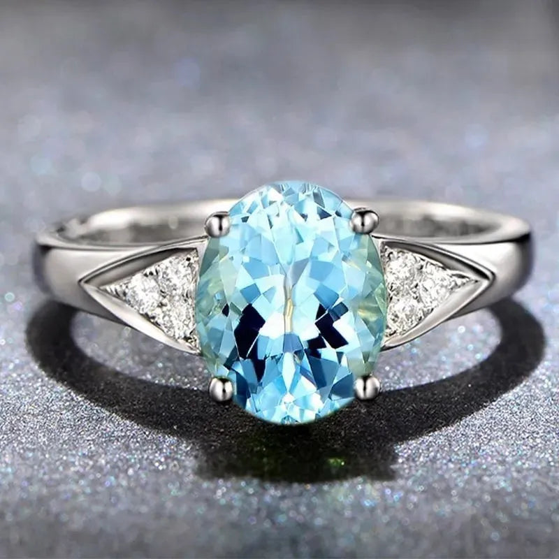 Close-up of a women's court-style silver-toned ring with an inlaid red natural zircon stone cut in a heart shape.