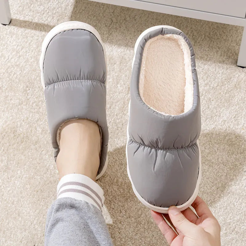 Blue down cotton winter slippers with a thick rubber sole and plush lining, shown on a wooden floor.
