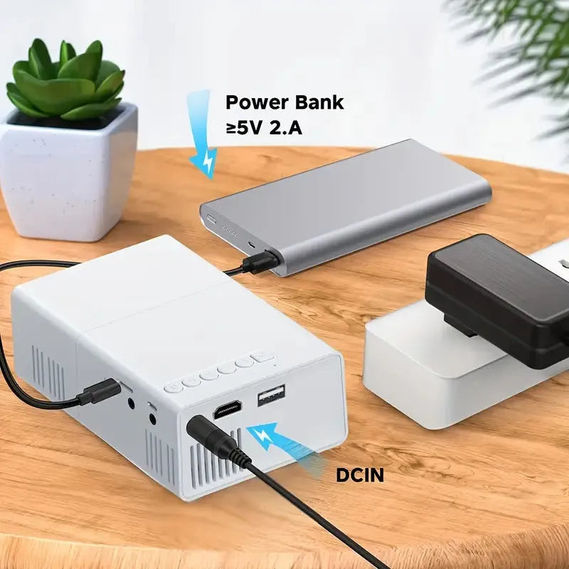 White or black M100 mini portable home projector with remote control on a table.