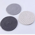 Three round cotton cord coasters in blue, measuring 18cm diameter, on wooden table