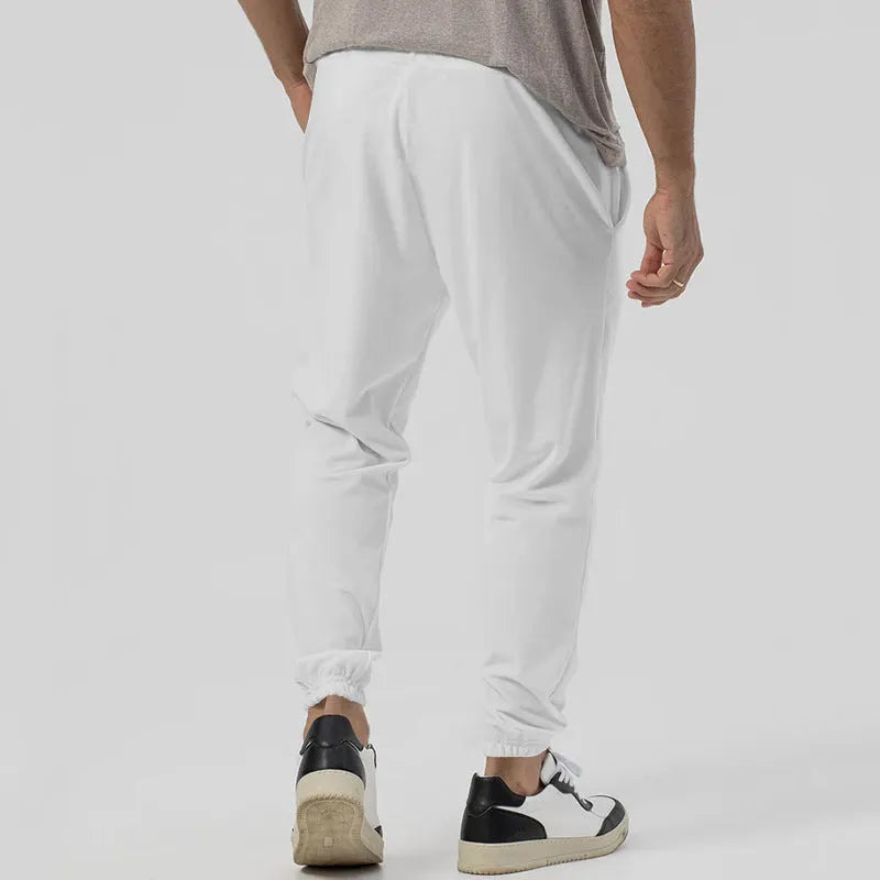 Man wearing grey loose tapered track sweatpants with a micro-elastic cotton blend fabric.