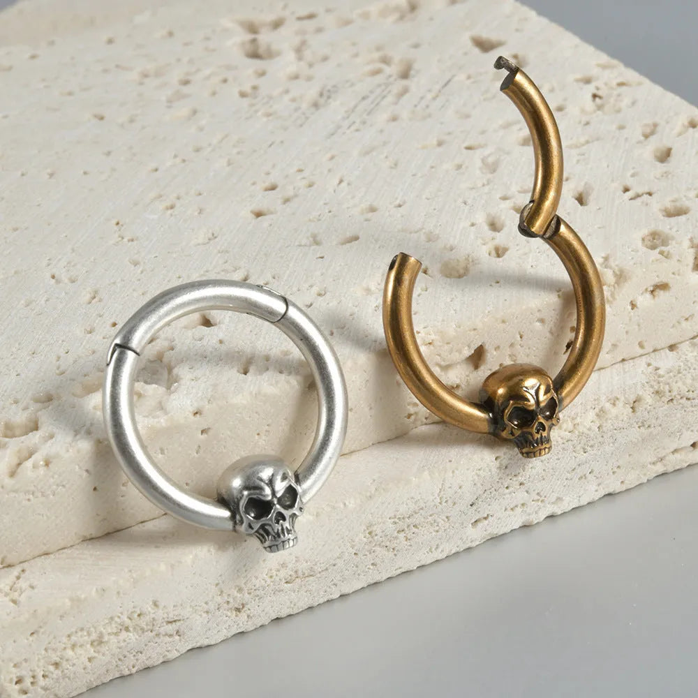 A pair of antique silver copper punk earrings featuring three small detailed ghost heads on a horizontal bar.