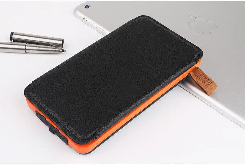 Outdoor solar power bank in black with a solar panel, soft leather finish, and LED light on a grassy field.