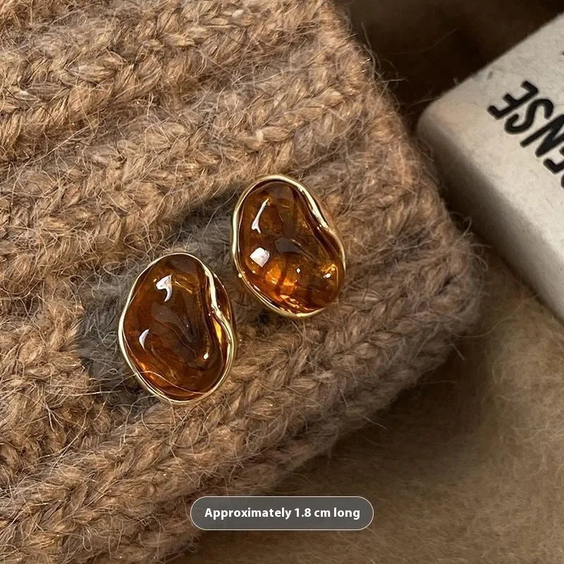 Set of three pairs of geometric holiday earrings: round studs, irregular amber studs, and tassel drop earrings.