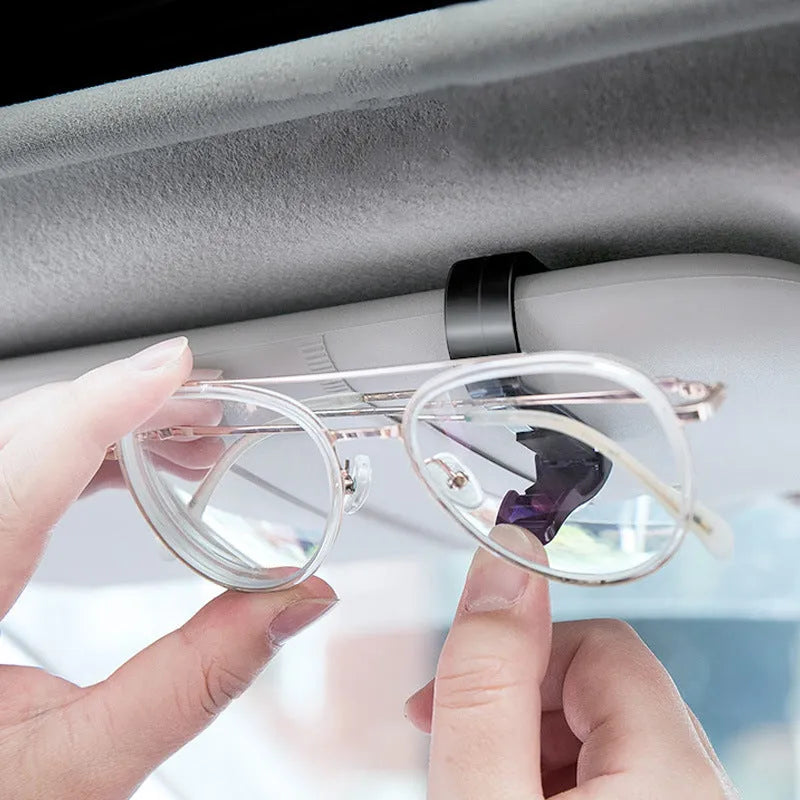 Black plastic multifunctional clip for car sun visors to hold tickets, IDs, or glasses.