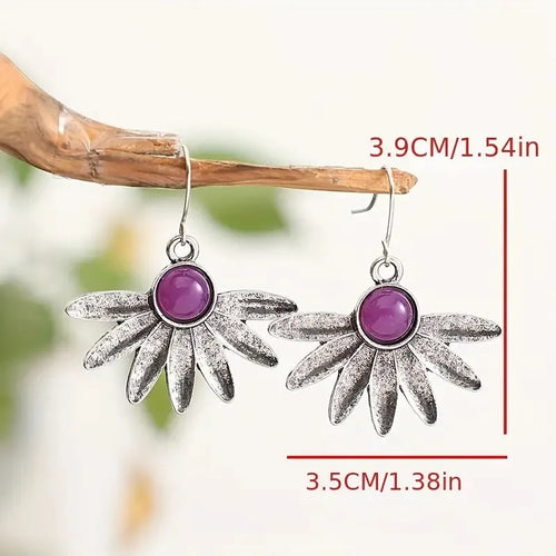 A pair of purple resin bohemian earrings with alloy details and animal or floral modelling on a white background.