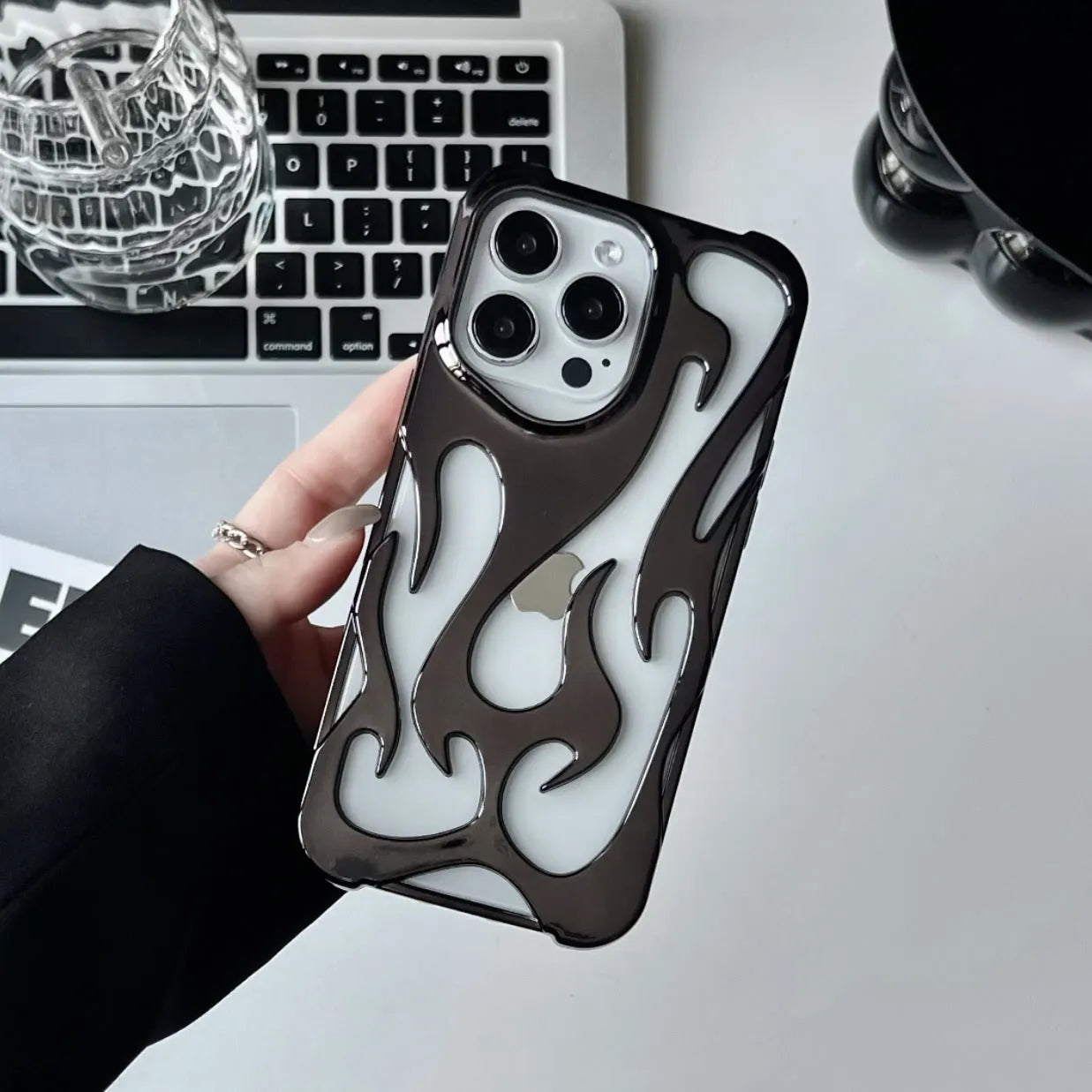 Silver electroplated iPhone case with hollow flame pattern design on a dark background