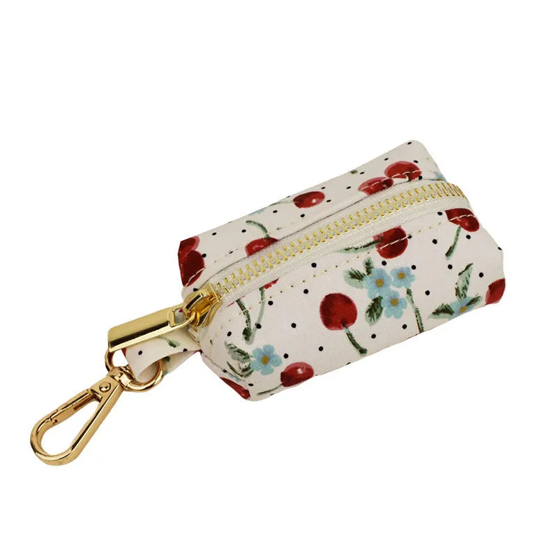 Red cherry print dog collar and leash set with light gold buckle, matching bow, vest, and poop bag.