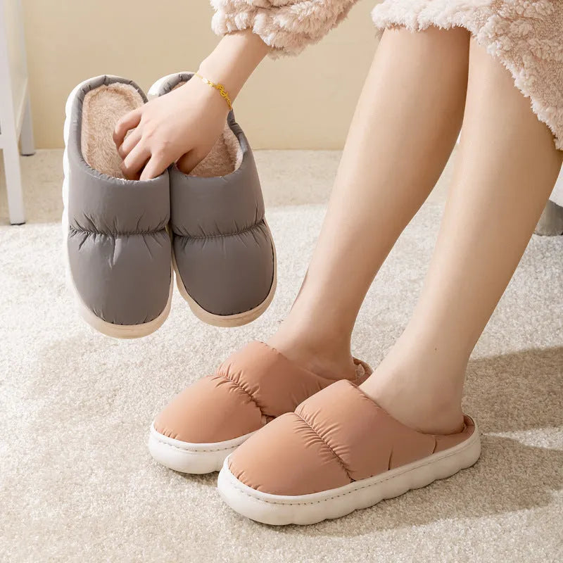 Blue down cotton winter slippers with a thick rubber sole and plush lining, shown on a wooden floor.