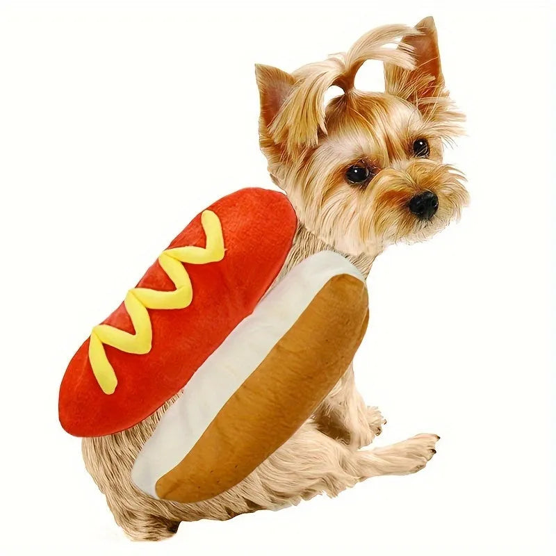 A small dog wearing a red and brown plush hot dog costume with a hood and leg openings.