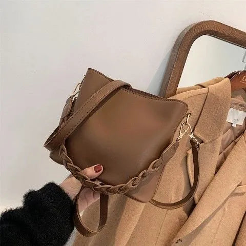 Retro style khaki crossbody bucket bag with weaving detail on the front.