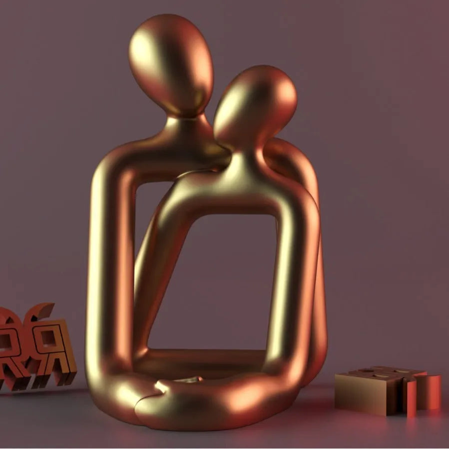 Modern resin couple statue in milky white or gold colour on a wooden surface.
