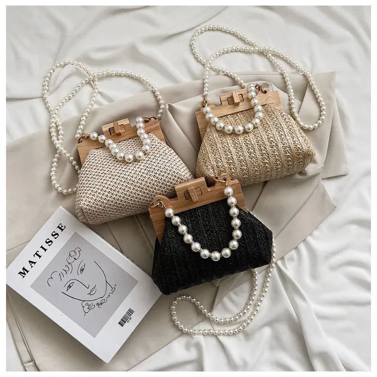 Women's woven straw shoulder bag with pearl chain detail showing horizontal square shape and multiple internal pockets