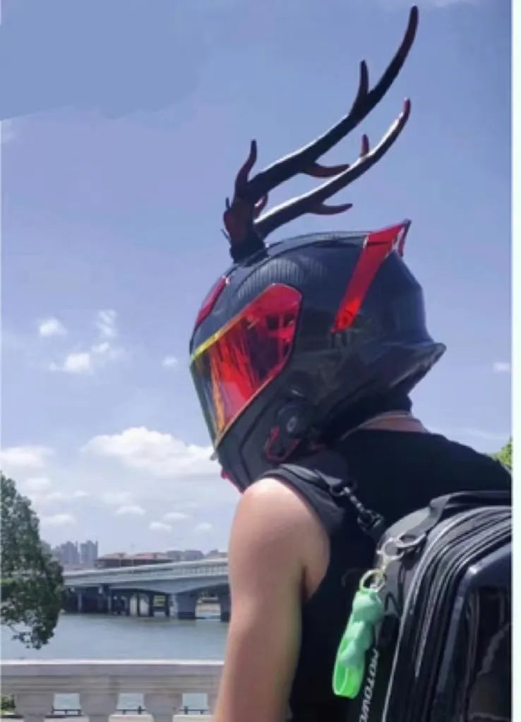 Pair of black resin dragon horn decorations next to a motorcycle helmet, showing scale and detailed texture.