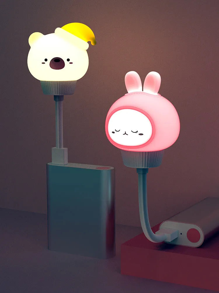 Cute cartoon animal USB night light in bear shape with remote control on a bedside table.