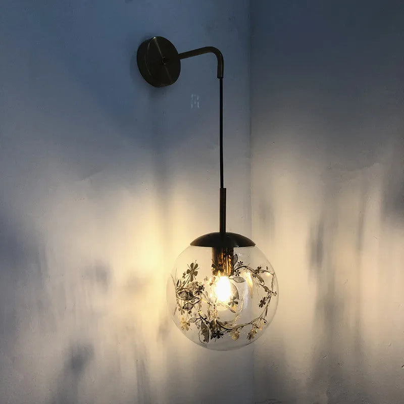 Modern golden flower glass wall lamp mounted beside a bed.