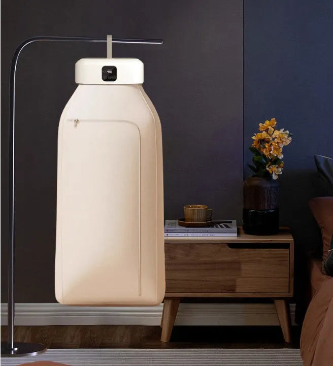 White cylindrical portable laundry drier dryer with remote control on a countertop.