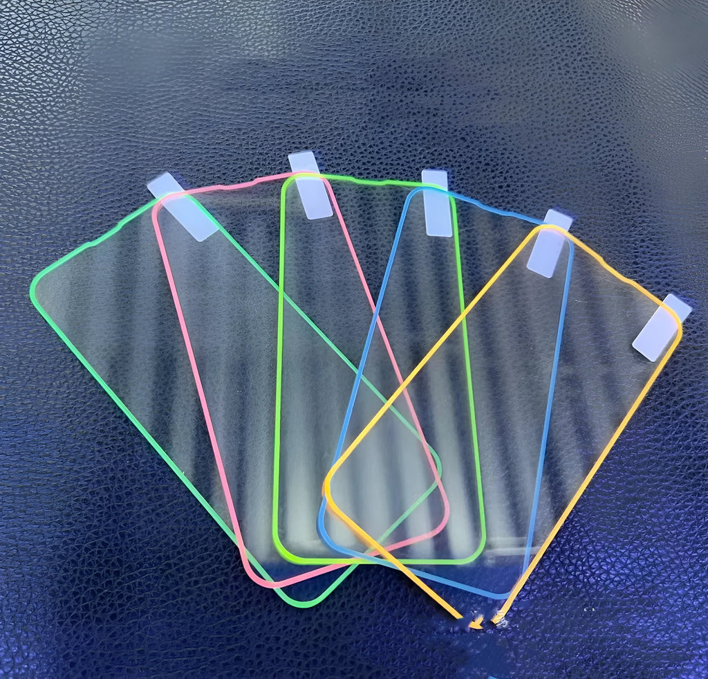 Fluorescent pink tempered glass screen protector glowing on an iPhone 13 in a dark room.