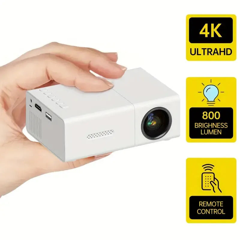 White or black M100 mini portable home projector with remote control on a table.