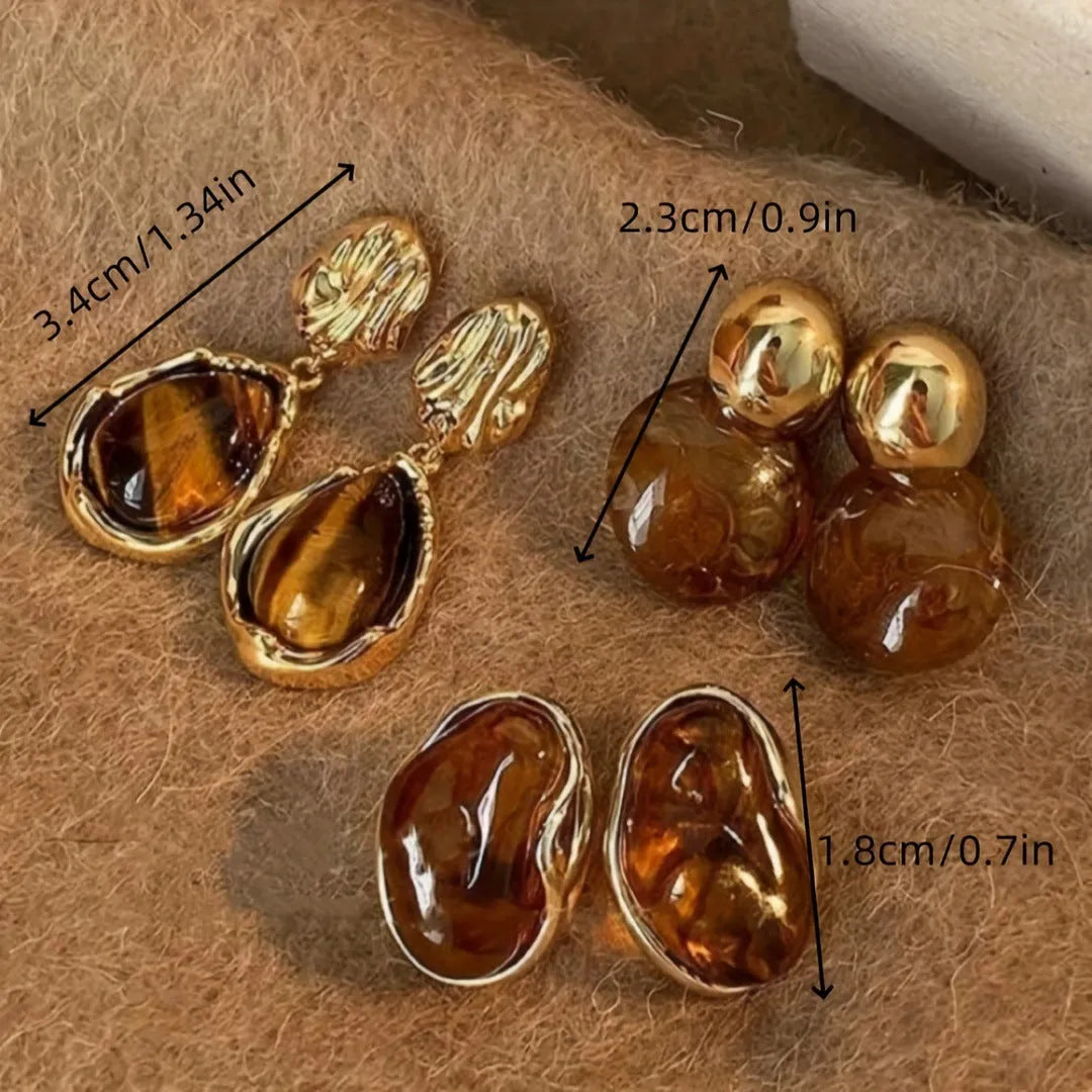 Set of three pairs of geometric holiday earrings: round studs, irregular amber studs, and tassel drop earrings.