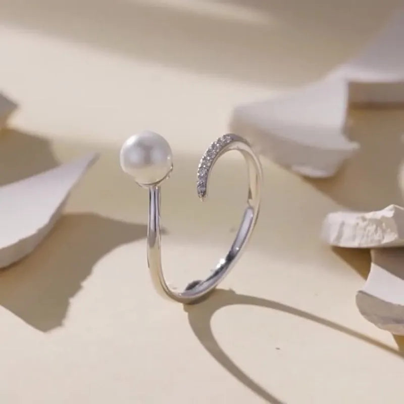 Silver-coloured adjustable open loop ring with a natural white shell pearl setting.