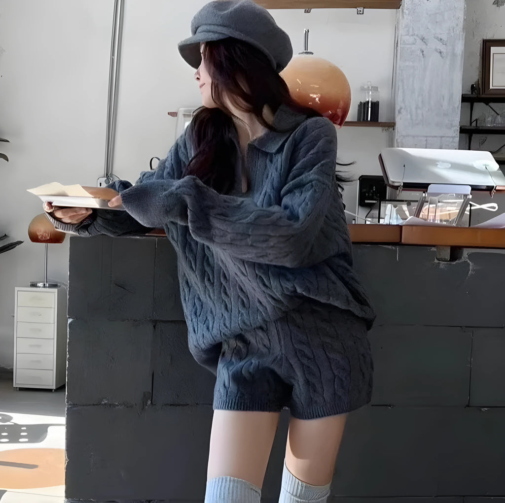 Woman wearing a creamy-white cable-knit long-sleeve sweater and matching elastic-waist knitted shorts from a two-piece set.