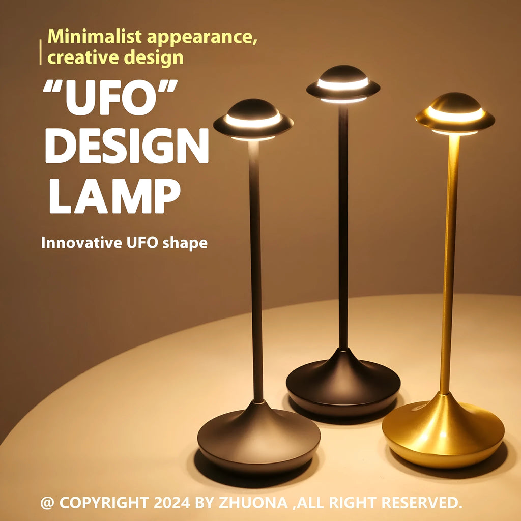 Modern metallic UFO-shaped table lamp with touch base in black, on a wooden desk.