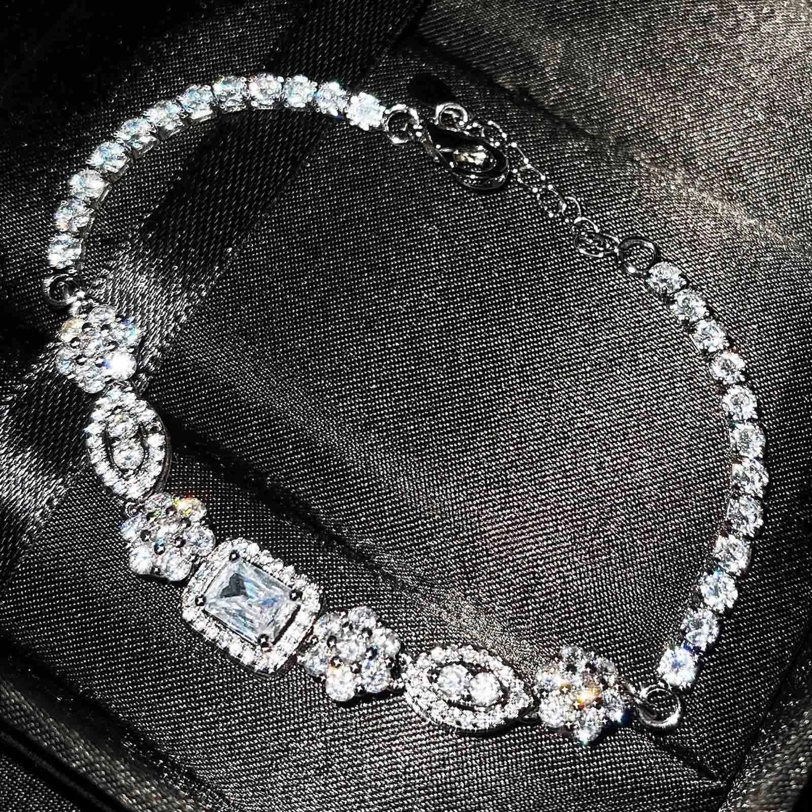 Women's geometric silver bracelet with inlaid zircon stones on a wrist, showing adjustable chain.