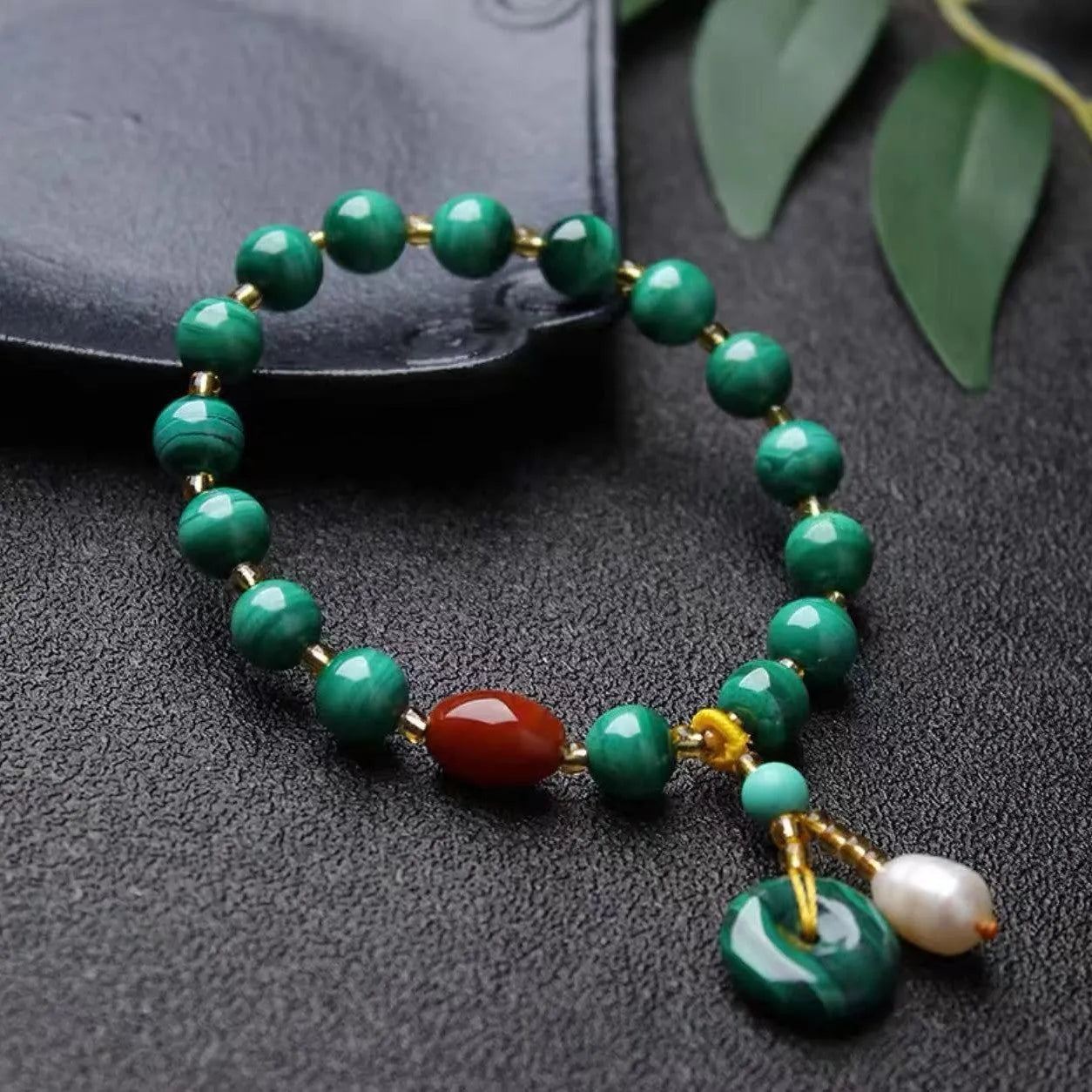Handmade natural malachite and red agate bracelet with 7-8mm barrel beads on a wrist.