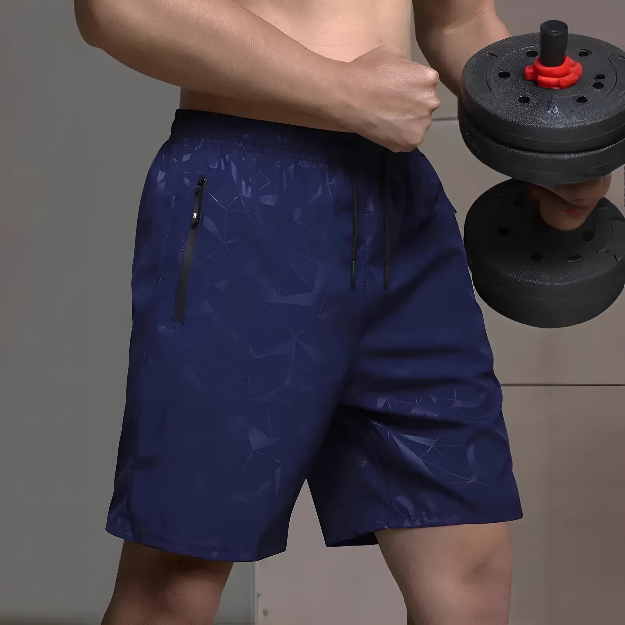 Man wearing loose-fit black printed sports shorts with an elasticated waist on a beach.