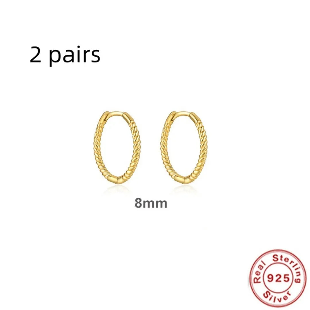 Close-up of a twisted sterling silver round hoop earring in gold colour, showing geometric design.