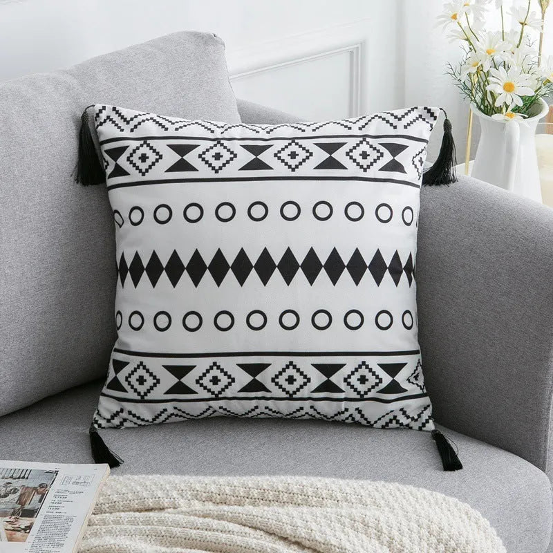 Bohemian style decorative throw pillow with polyester cover in light grey on a sofa.