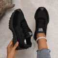 Black mesh sports flat shoes for women with synthetic leather upper and rubber sole, side view