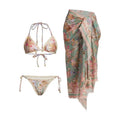 Women's creamy-white floral bikini swimsuit set with matching skirt on a beach background.