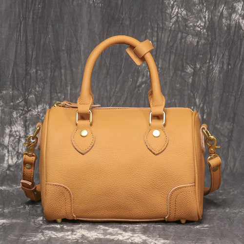 Brown yellow cowhide leather Boston bag with single shoulder strap, showing cylindrical shape and open outer pocket.