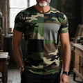 Man wearing a loose-fit grey t-shirt with a large-scale colourful retro pattern printed across the chest.